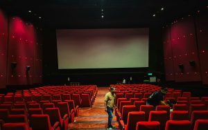 Cinema hall with rows of red seats facing a large screen