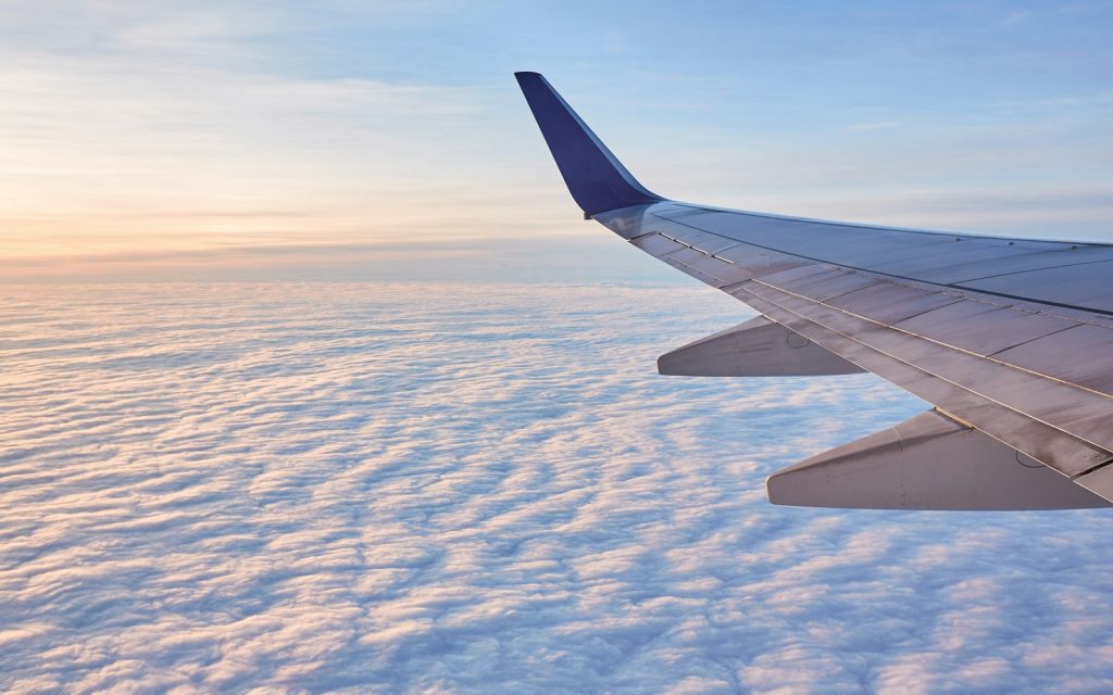 An airplane wing above white clouds