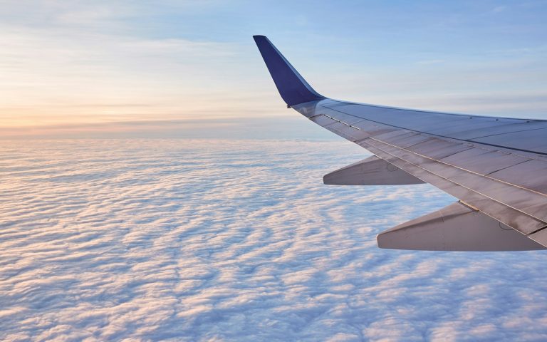An airplane wing above white clouds