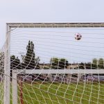 A football flying toward the goal net