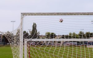 A football flying toward the goal net