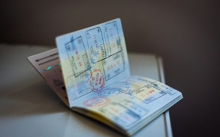 An open passport filled with ink entry stamps on a table