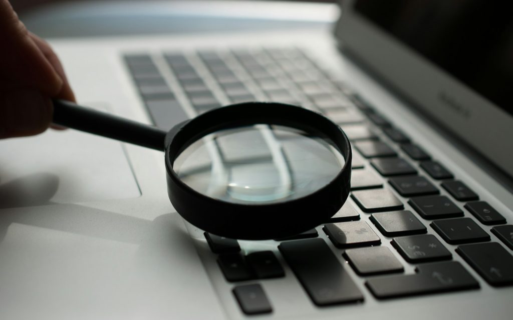 Magnifying glass resting beside a laptop computer