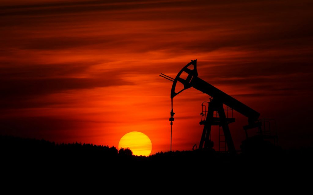 Silhouette of an oil pump jack against a red sunset