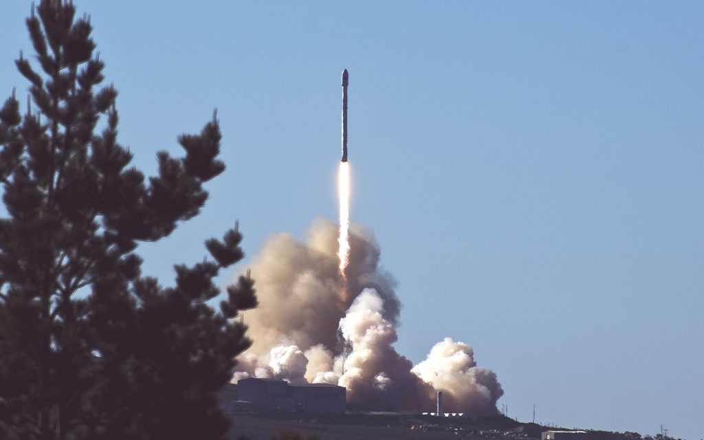 A rocket lifting off from the launch pad with a bright exhaust plume