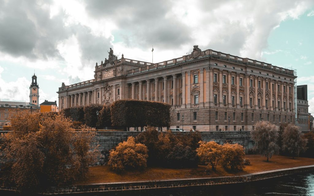 Grand classical building beside a river framed by autumn trees