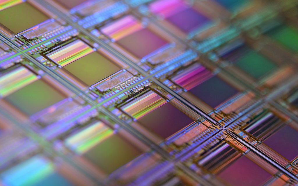 A silicon wafer covered in a grid of iridescent microchip dies