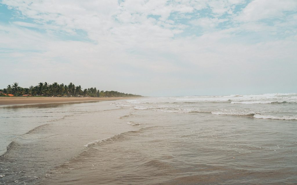 Waves rolling onto a sandy beach along a tropical coastline